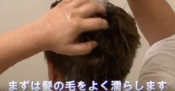 髪をシャワーで濡らしている男性